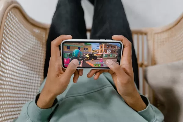 Para dłoni trzymająca telefon grający w fortnite z magnetycznym spustem przymocowanym do telefonu